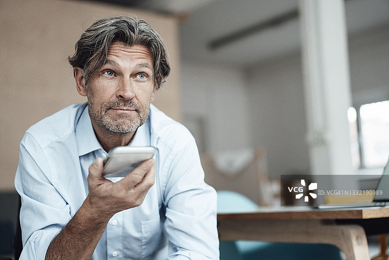年长的商人在办公室里用智能手机交谈图片素材