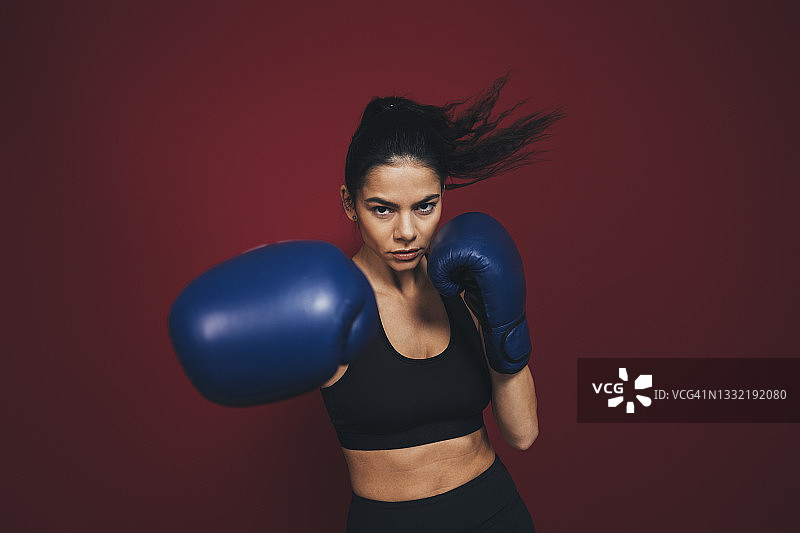 女人在栗色背景前练习拳击图片素材