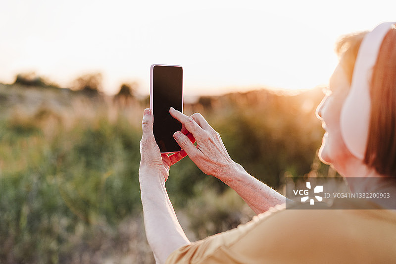 年长的女人在日落时远足时使用手机图片素材