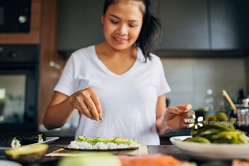 女厨师在寿司上撒上黑白芝麻图片素材