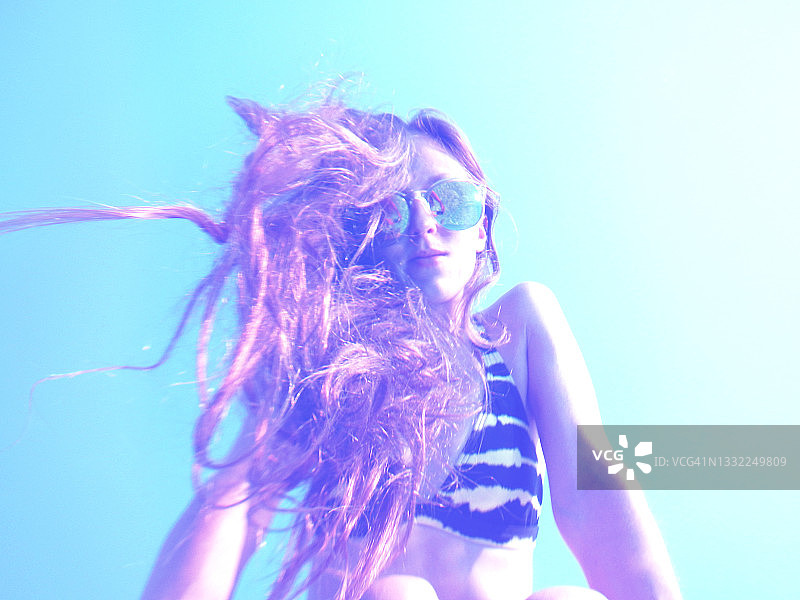 长发飘逸：在夏季假期戴着太阳镜的年轻女人图片素材