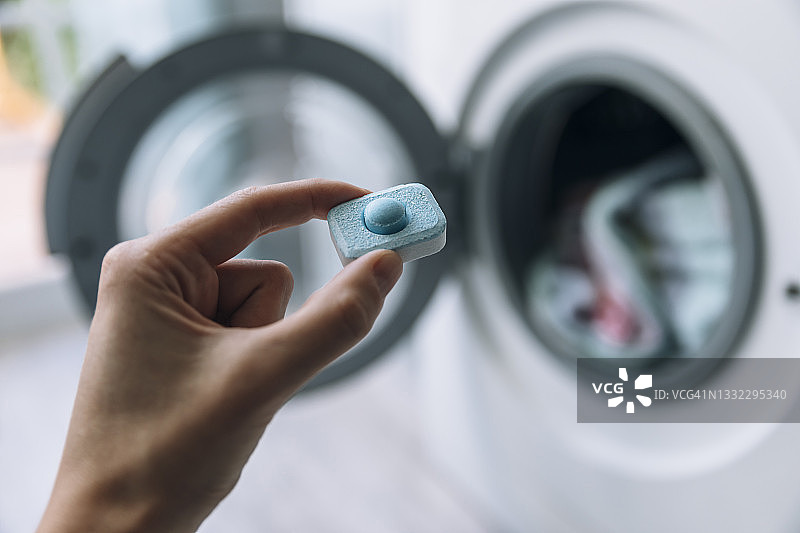 手持洗衣凝珠，洗衣机背景图片素材