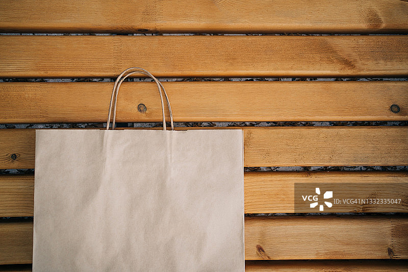 放置在木板上的环保购物手柄棕色纸袋，具有设计文案空间图片素材
