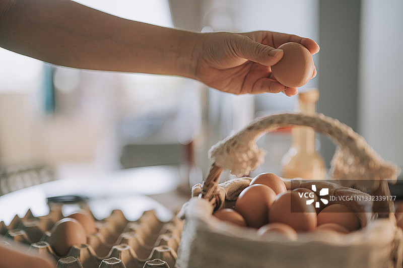 中国妇女将鸡蛋从纸箱放入家中的篮子里图片素材