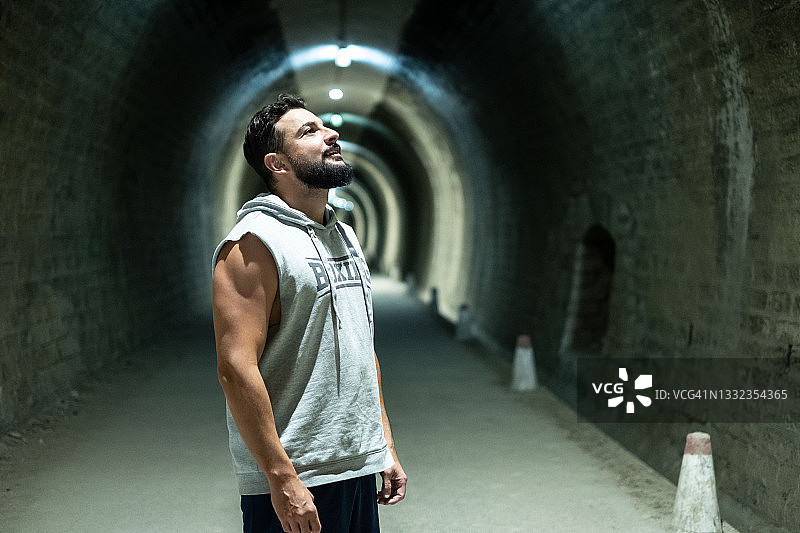 隧道中戴着胡须和头戴运动帽的男子向上看图片素材