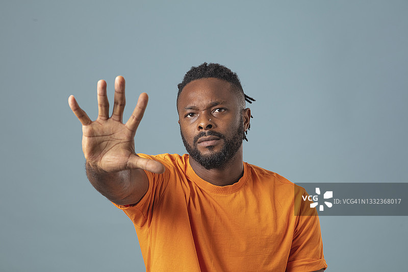 留着脏辫的英俊男人在蓝色背景上做出“停止”或“拒绝”的手势，捍卫权利图片素材