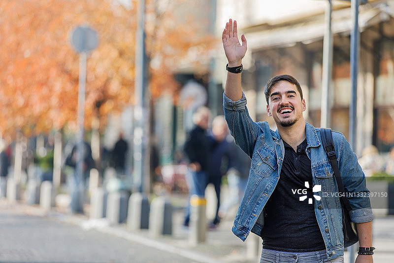 一位年轻男子站在街上挥手招出租车图片素材