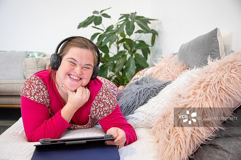 患有唐氏综合征的成年女人躺在沙发上看设备图片素材