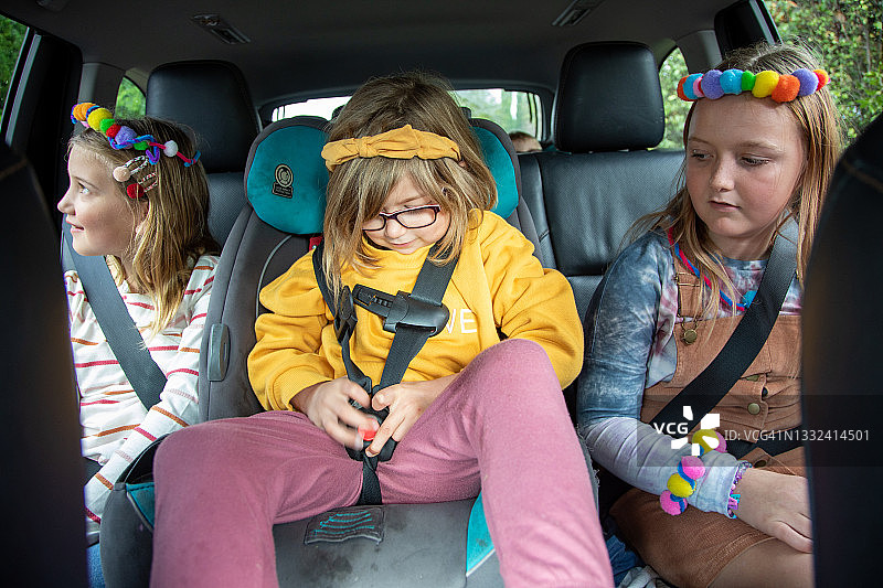患有自闭症的女孩和兄弟姐妹一起系好安全带图片素材