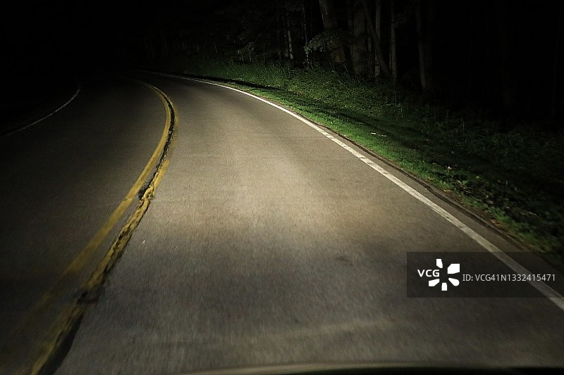 车头灯照亮黑暗的乡村公路图片素材