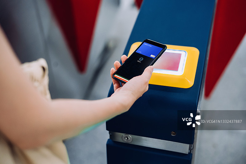 年轻的亚洲女性在地铁站使用智能手机进行非接触式支付图片素材