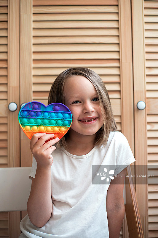 微笑的女孩拿着彩色按压式抗压玩具图片素材