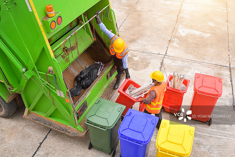 两名清洁工站在垃圾车旁倾倒垃圾箱，泰国图片素材