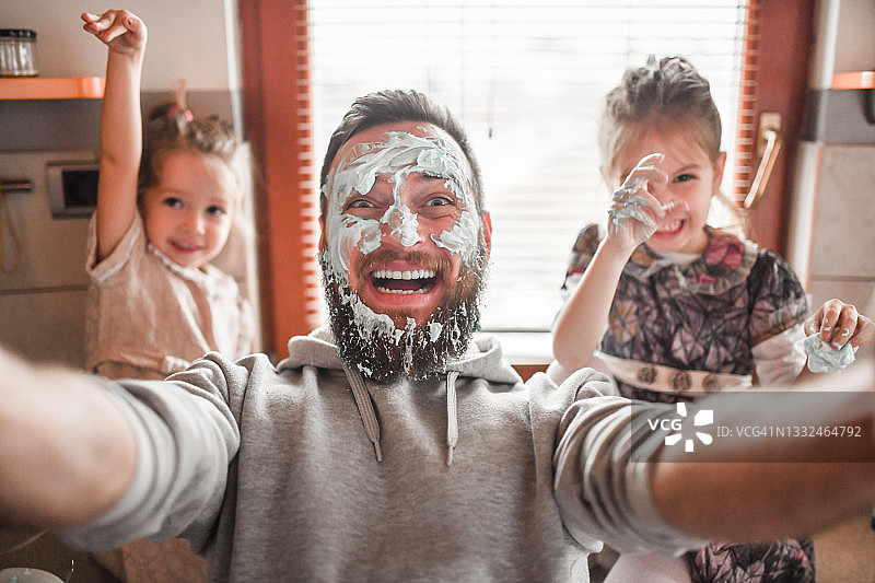 父亲和女儿一起做甜点，脸上沾满奶油自拍图片素材