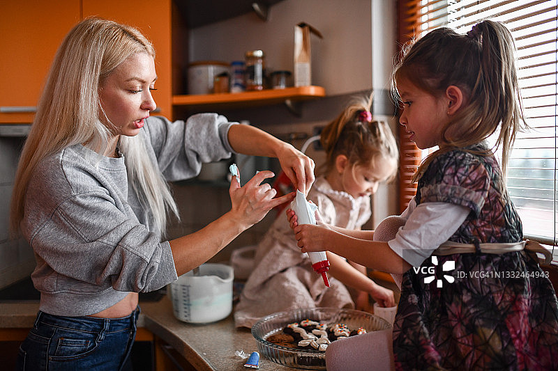 母亲和小女孩在厨房装饰饼干图片素材