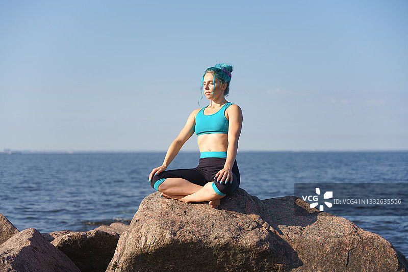 穿着瑜伽服在海边冥想的年轻女子图片素材