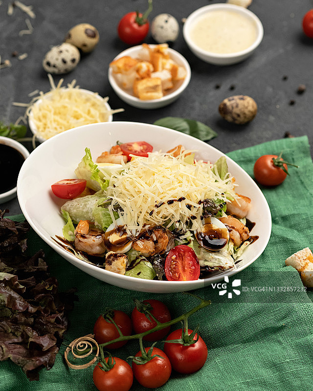 鲜虾沙拉配磨碎的奶酪，海鲜鹌鹑蛋凯撒沙拉，绿色粗麻布上的白色碗，特写镜头，柔焦，竖版构图图片素材