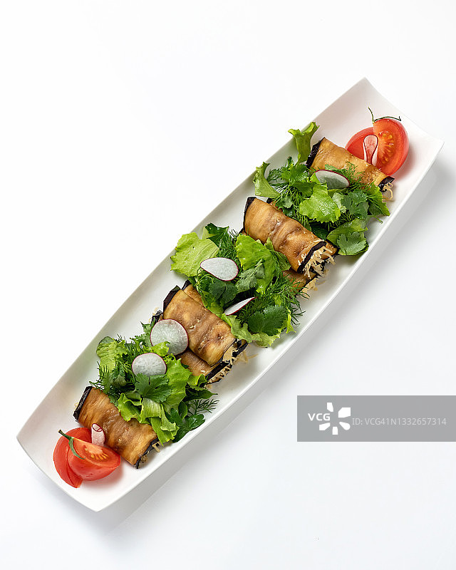 茄子卷：蔬菜开胃拼盘，配以绿色蔬菜，在白色背景下隔离。油炸茄子片卷，配以西红柿和欧芹。时令食品。竖版照片图片素材
