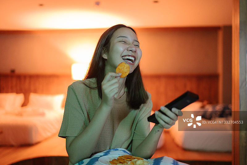 快乐的女人享受在晚上看电视。图片素材