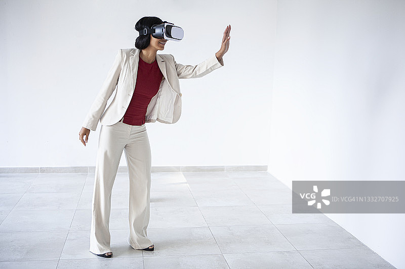 穿着正式服装的拉丁裔女人在使用虚拟现实眼镜时玩得很开心图片素材
