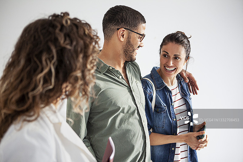 拉丁裔夫妇拿着智能手机与房地产经纪人交谈图片素材