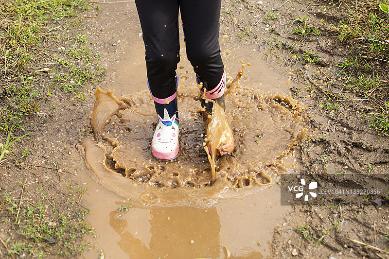 跳跃时在泥坑里泼水的女孩图片素材