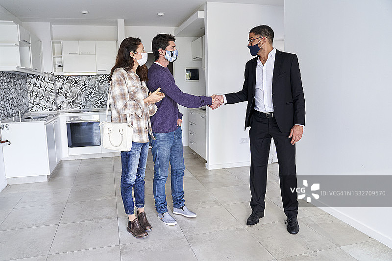 佩戴口罩的中年夫妇与房地产经纪人握手看房图片素材
