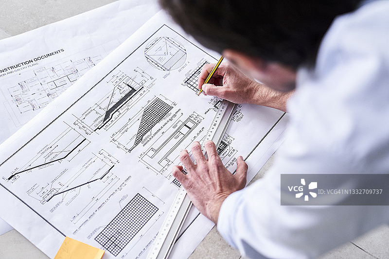 中年男建筑师在地板上改进房屋蓝图特写图片素材