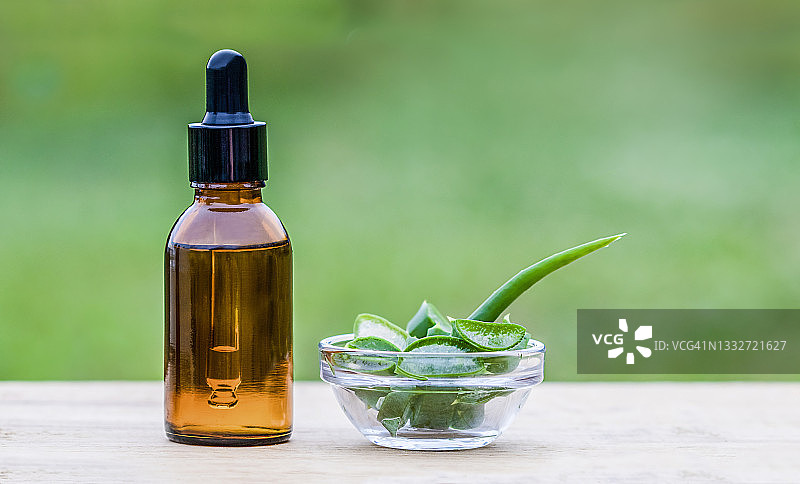 木桌上的芦荟叶和滴管化妆品瓶图片素材