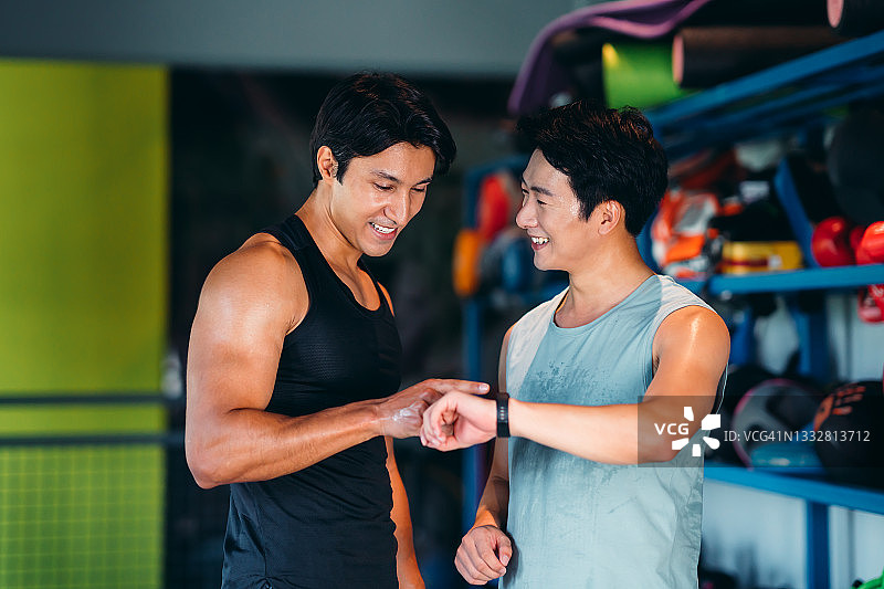 在健身房训练后检查健身追踪器数据的健壮人群，健康和健身概念图片素材