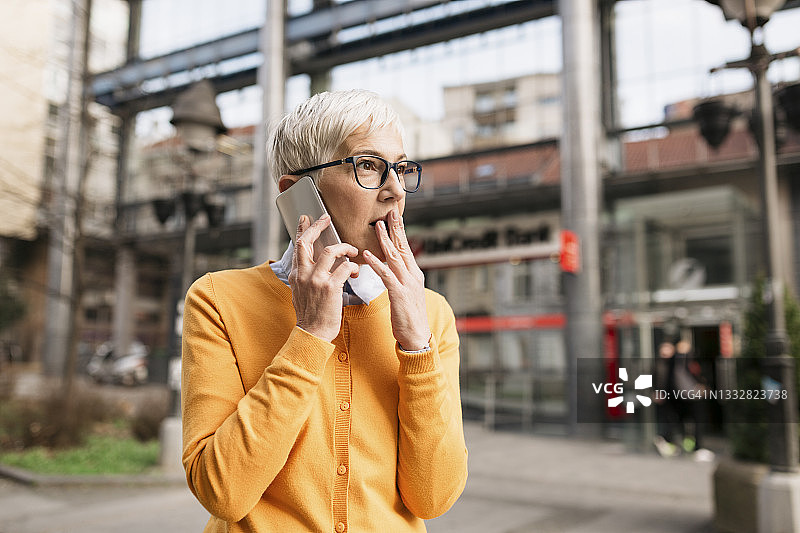 在城市中使用智能手机的年长的白人妇女图片素材