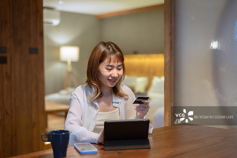 亚洲女人晚上在家用笔记本电脑在线购物支付图片素材