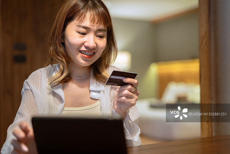 亚洲女人晚上在家用笔记本电脑在线购物支付图片素材