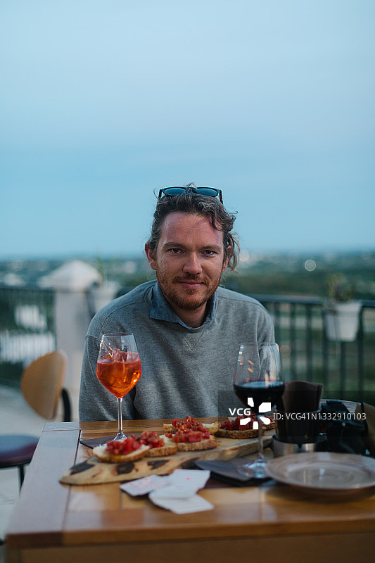 年轻男人在屋顶露台享用开胃酒图片素材