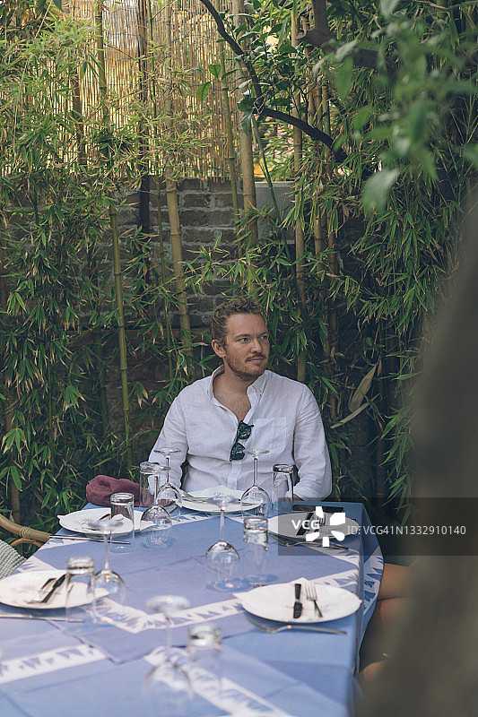 年轻男子坐在户外餐桌旁图片素材