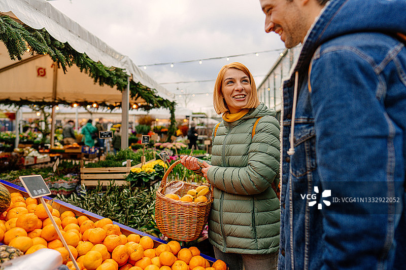 在当地食品市场上购买水果的微笑情侣图片素材