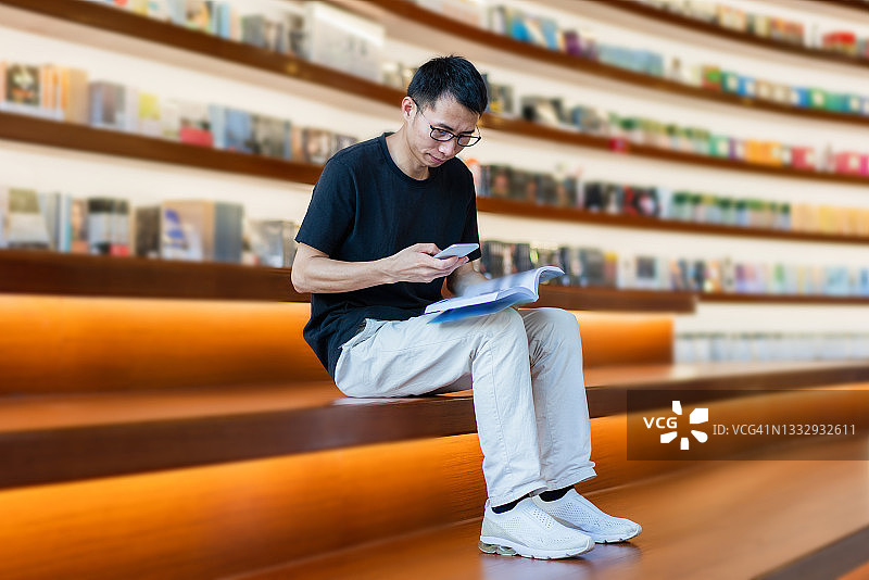 正在阅读时拿起智能手机回复消息的亚洲商人图片素材