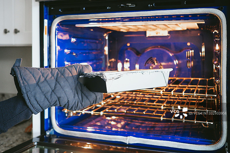 女人将烤盘放入烤箱图片素材
