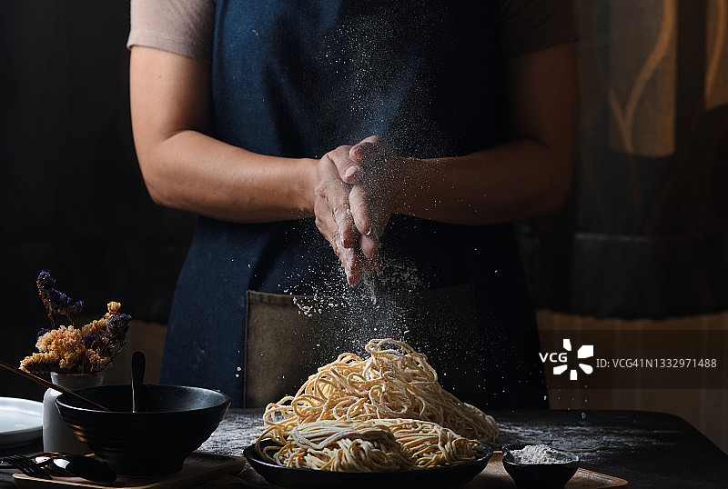 女人在黑色桌子上制作鸡蛋面条的手部图片素材