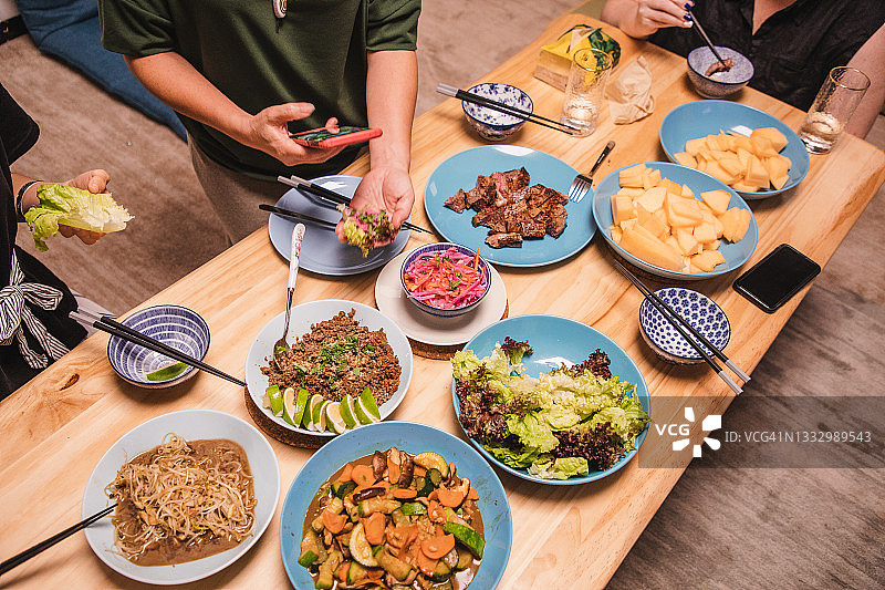 朋友们一起享用晚餐，并用手机拍摄食物照片图片素材