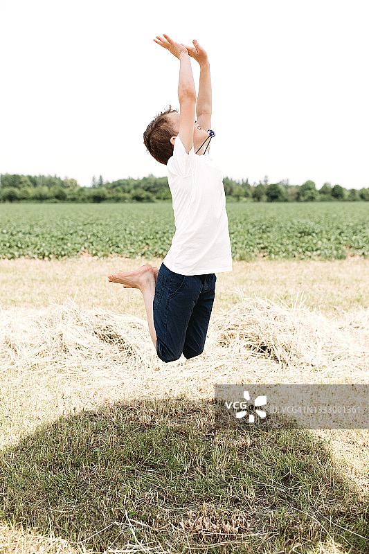 在草地上高兴跳跃的男孩图片素材