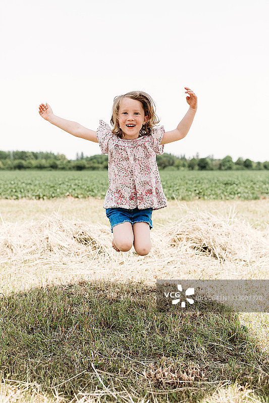 在草地上高兴地跳跃的小女孩图片素材