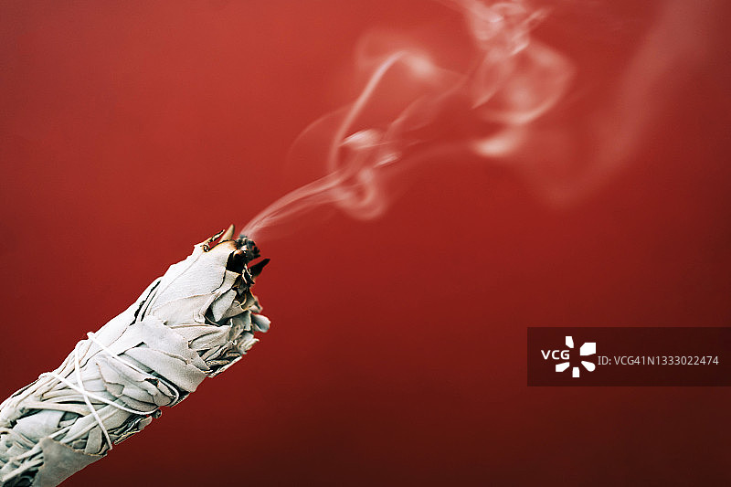 女士手持燃烧的白鼠尾草图片素材