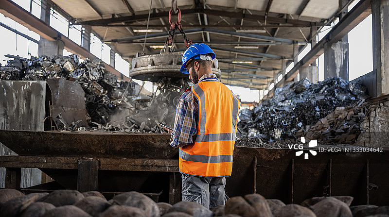 身穿反光背心的男人站在金属废料大厅里图片素材