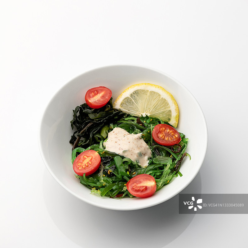 海藻沙拉配樱桃番茄和柠檬，白色背景亚洲美食图片素材
