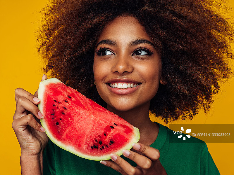 手拿西瓜的漂亮非洲裔女孩的棚拍肖像图片素材
