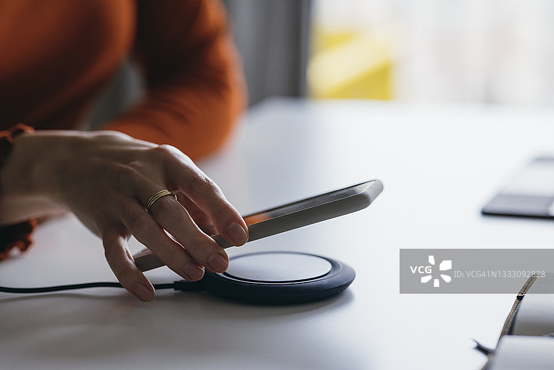 女人将手机放在无线充电器上图片素材