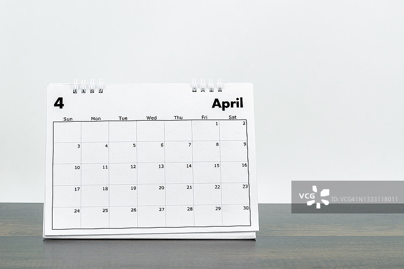2022年4月台历，用于在木桌上规划和提醒，白色旧水泥墙背景图片素材