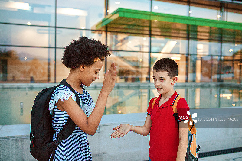 两个孩子在校园里打招呼，互相击掌图片素材