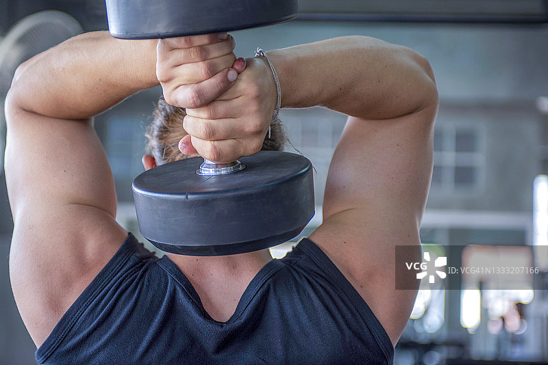 男人在健身房用哑铃锻炼图片素材